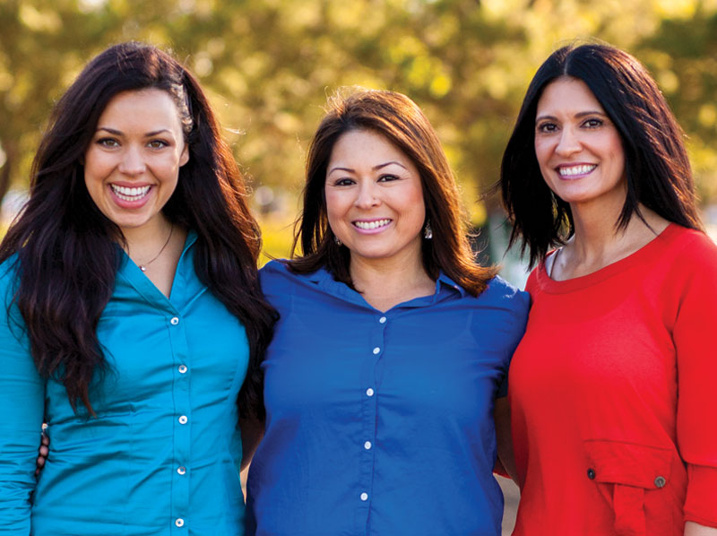 Three women smiling outdoors.