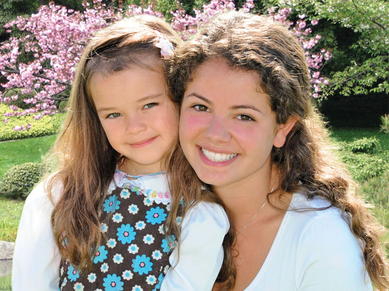 two smiling sisters in a garden